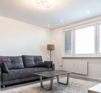 Living room with a dark sofa, coffee table, and floor lamp in a three-room apartment.