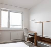 A desk with a chair and a cabinet in a 3-room apartment with white walls.