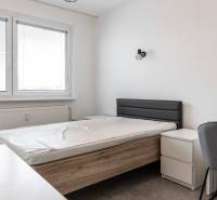A bedroom with a bed and furniture in a 3-room apartment, light walls, a window with blinds.