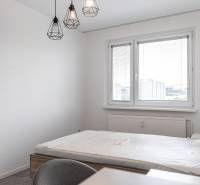 A bedroom with a bed, a desk, and hanging lamps in a 3-room apartment.