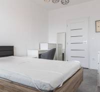 Bedroom in a 3-room apartment with a bed, table, and chair, in light shades.
