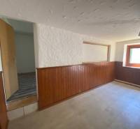 A room with wooden paneling and a window, part of apartment construction.