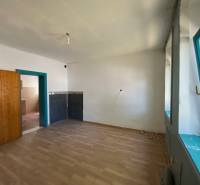 A room with a wooden floor, a window, and a door, suitable for apartment construction.