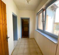 A narrow corridor with light walls and wooden doors in an apartment building under construction.