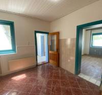 A room with windows and doors, a light ceiling and tiles, apartment construction.