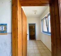 A room with a wooden door frame, tiles, and blue windows under apartment construction.