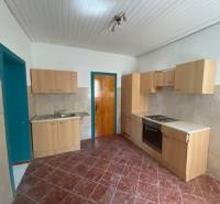 A kitchen with wooden cabinets, a sink, and a stove in apartment construction.