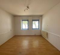 A spacious room with wooden flooring, white walls, and two windows, Apartment construction.