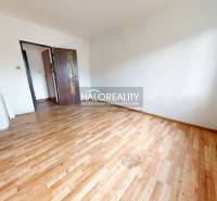 A spacious room with wooden flooring in a 3-room apartment, bright walls, and a large window.
