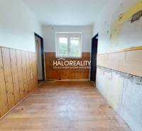 A hallway of a 3-room apartment with older wooden paneling and a window.