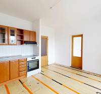 A kitchenette in a studio apartment with wooden cabinets and a stove.