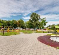 The children's playground on Blagoevova Street in Petržalka with climbing frames surrounded by greenery and apartment buildings.