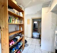 A hallway in a family house with a shoe rack and books on a shelf.