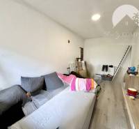 Living room with a sofa, television, shelf, and stairs in a family house.