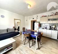 Living room with kitchen in a family house, comfortable sofa, wooden table, white sideboard.