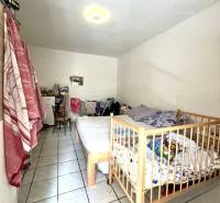 Children's room with white walls, tiled floor, and a crib in a family house.