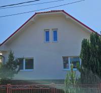 A family house in Liptovská Osada with a sloped roof and a fence surrounded by greenery.
