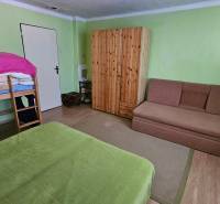 A room in a family house with a bunk bed, a sofa, and a built-in wardrobe.