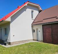A family house in Liptovská Osada with a red roof and an extension with garage doors.