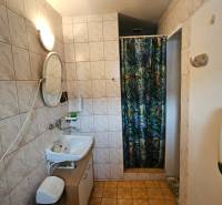 Bathroom in a family house with a sink, shower, and tiled walls.