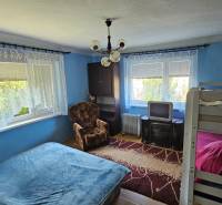 Blue room in a family house with a bed, bunk bed, television, and an armchair.