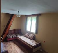 Living room in a cabin with wooden flooring, a sofa, and a staircase.