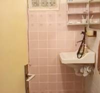 A bathroom in a cottage with pink tiles and a sink with a large faucet.