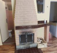 Interior in a cabin with a fireplace, parquet flooring, and entrance to the bathroom.