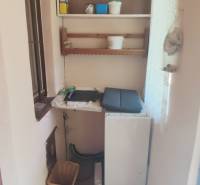 Interior of a cabin with a small kitchenette, shelves, and storage space.