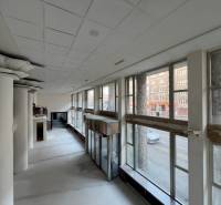 Commercial spaces with large windows and massive columns, offering a view of the street.
