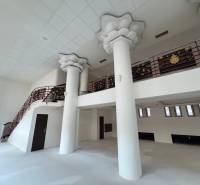 Interior of commercial premises with a staircase, white walls, and decorative ceiling columns.