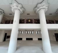 Interior of commercial spaces with large columns and decorative railing on the upper floor.