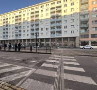 Pedestrian crossing and a line of people in Bratislava on Krížna Street in front of commercial premises.