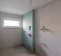 Unfinished bathroom in a 2-room apartment with a window and preparation for installations.