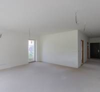 A spacious room in a 2-room apartment with bare walls and prepared electrical wiring.