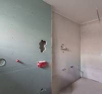 An empty room in a two-room apartment with prepared wiring and a drywall wall.