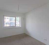 An empty room with a large window and an unfinished floor in a two-room apartment.