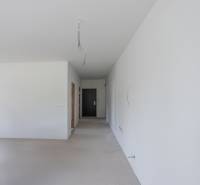 An empty room with white walls in a 2-room apartment, electrical wires hanging from the ceiling.
