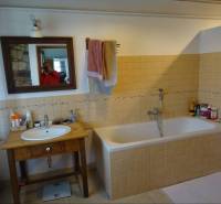 A bathroom in a family house with a bathtub, mirror, and wooden sink.