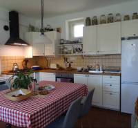 A family house kitchen with wooden furniture, a checkered tablecloth, and kitchen appliances.