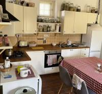 A kitchen in a family house with white cabinets and a checkered tablecloth on the table.