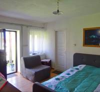 Interior of a family house with a bed, an armchair, and open doors to the terrace.