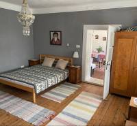 Bedroom in a family house with a wooden bed and dresser, leading to the dining room.