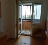 Windows with a balcony and a radiator in a 3-room apartment, simple flooring.