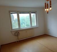 An empty room with a hanging light fixture and a window in a three-room apartment.