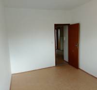 Empty room with a door in a 3-room apartment, parquet floor, white walls.