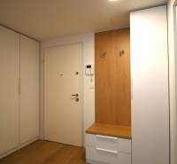 Hallway in a 2-room apartment with white cabinets and a wooden coat rack.