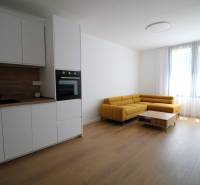 Living room in a two-room apartment with a white kitchen and a yellow sofa, bright environment.