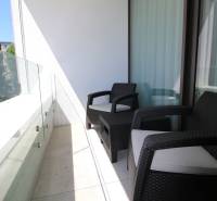 A balcony with two chairs and glass railing in a 2-room apartment.