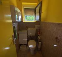 Yellow bathroom in a family house with a sink, toilet, and window.